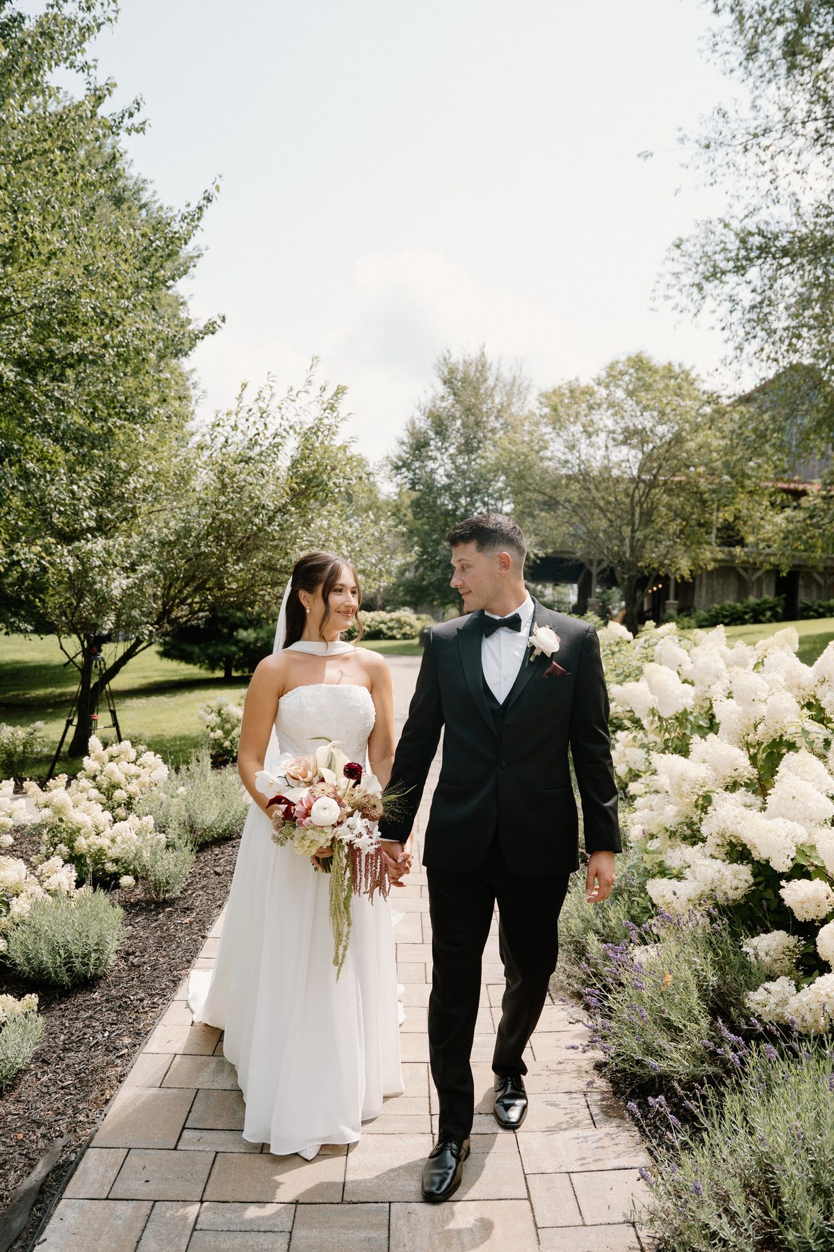 Bride and groom walking through a garden path on their wedding day